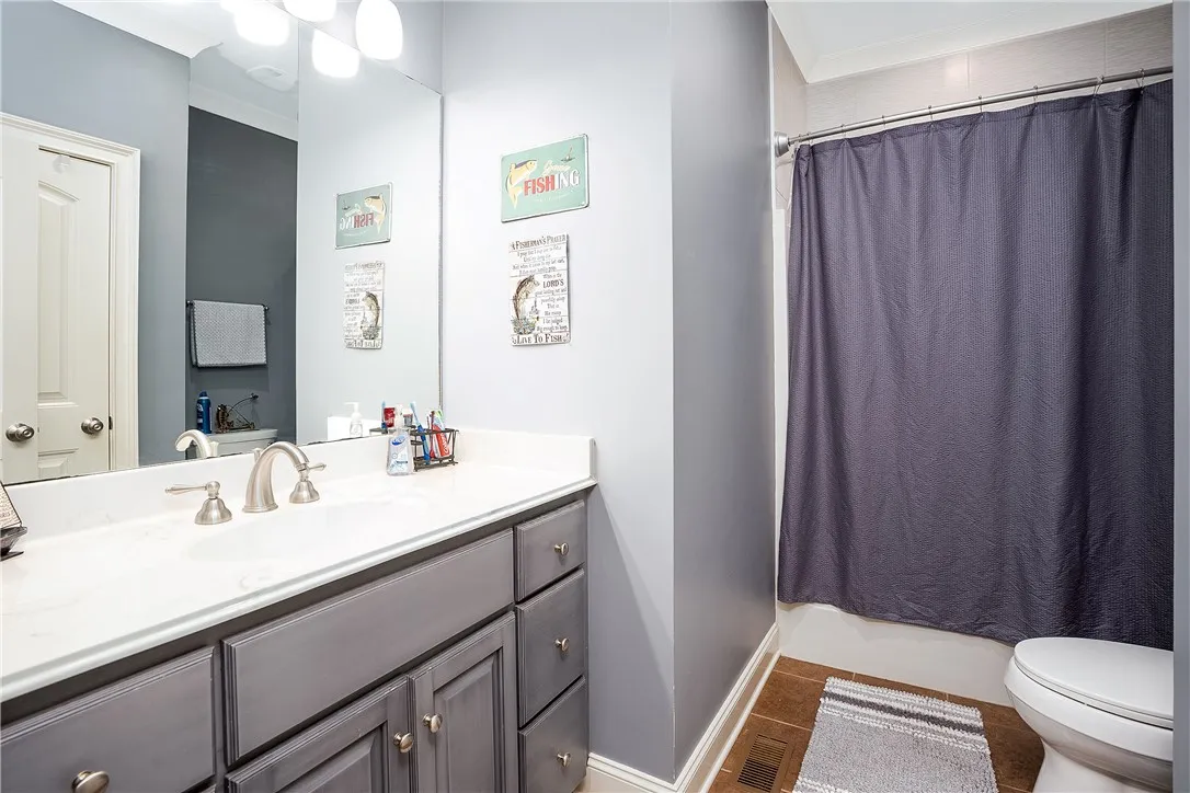 A neutral-toned vanity with brushed nickel hardware grounds this well-appointed bathroom.