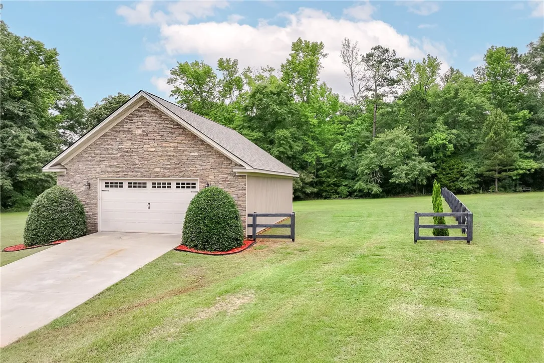 A stone-clad garage with a pristine driveway offers ample parking space amidst natural surroundings.