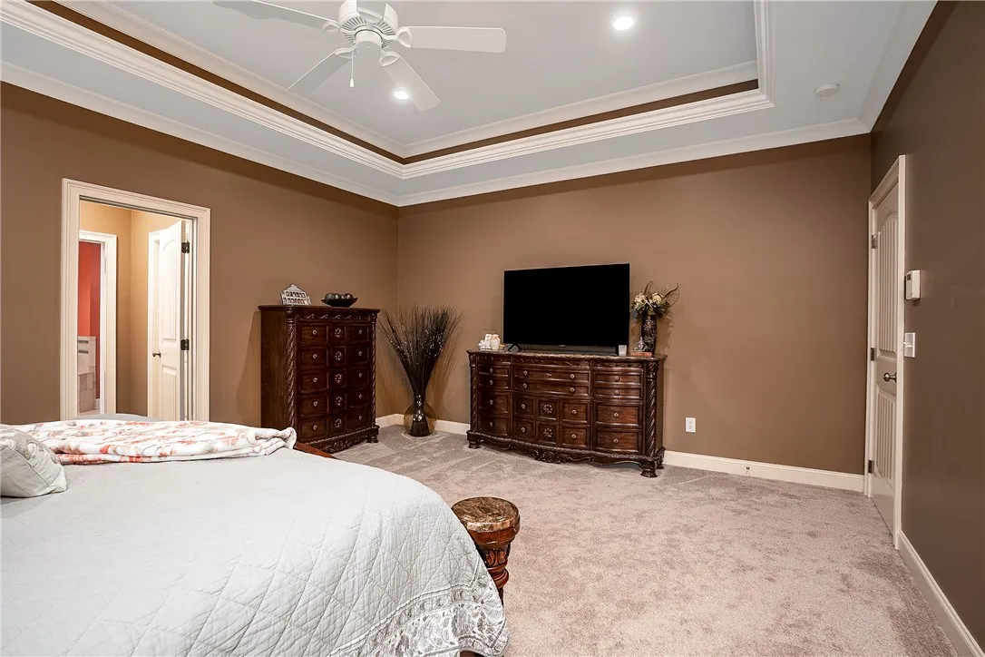 Luxurious tray ceilings crown this well-lit, carpeted sleeping area with an adjoining private bath.
