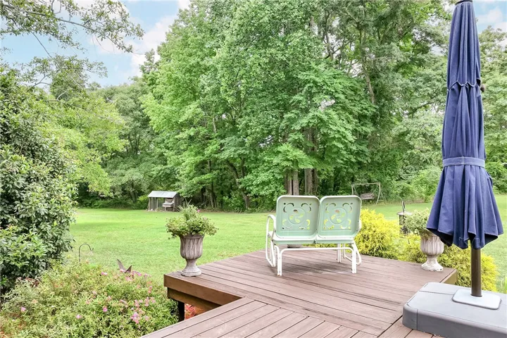A spacious wooden deck extends into a verdant yard, offering tranquil outdoor enjoyment.
