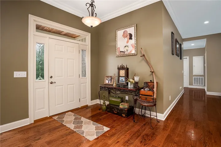 Enter into a warm and welcoming foyer featuring a polished hardwood floor and crown molding.