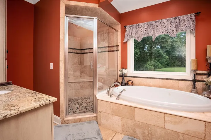 Luxurious bathing experience with a tiled corner tub and a spacious glass-enclosed shower.