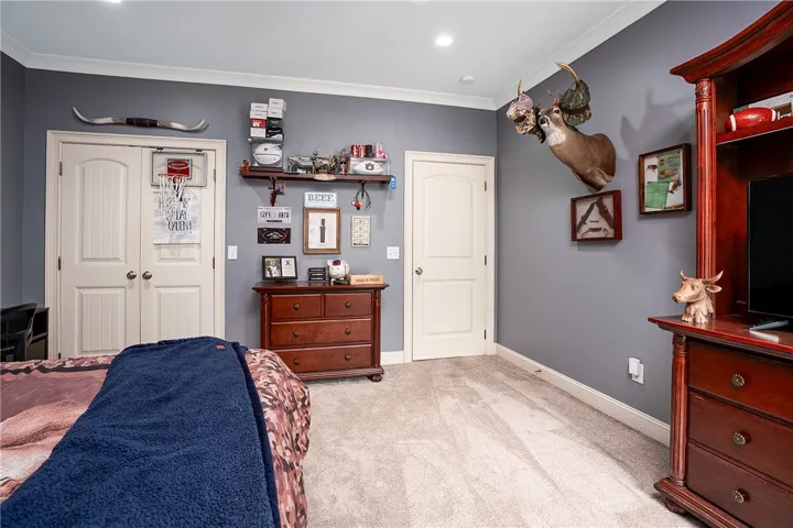 An inviting bedroom with plush carpet and crown molding, offering ample space and dual doors.