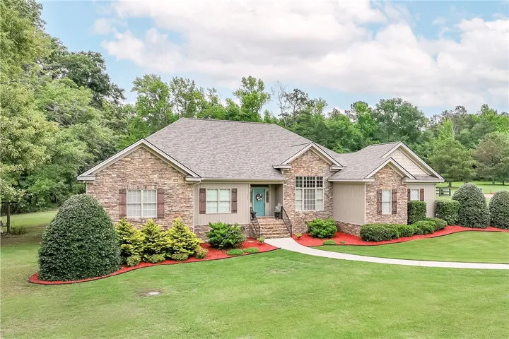 A welcoming stone and siding facade with vibrant landscaping and a neatly manicured lawn.