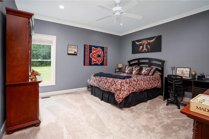 A comfortable bedroom features plush carpeting and a tranquil window view of natural surroundings.