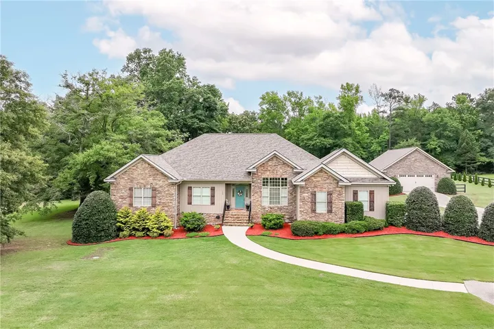 A graceful home with a stone and wood facade, featuring manicured landscaping and a long inviting pathway.