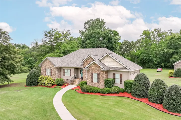 A graceful paved path guides you to a charming residence, framed by mature plantings and lush green lawns.
