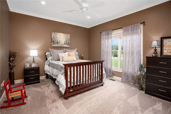 A well-lit bedroom provides comfortable repose with carpeted flooring and outdoor views.