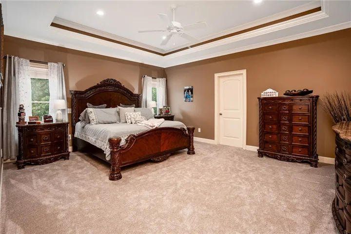 A spacious sleeping quarter showcasing a detailed tray ceiling and plush carpet underfoot.