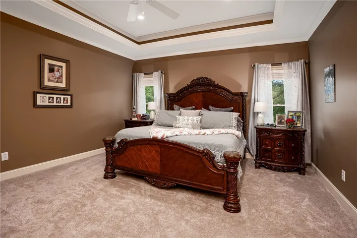 A tray ceiling and abundant natural light create an inviting primary bedroom retreat.