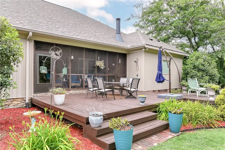 A spacious wooden deck provides ample outdoor living space, complete with a screened-in porch for bug-free enjoyment.