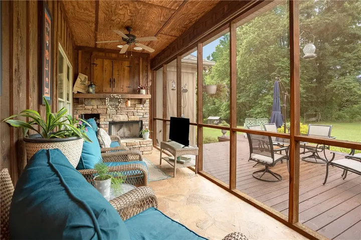 A rustic screened porch with a stone fireplace offers comfort and outdoor living.