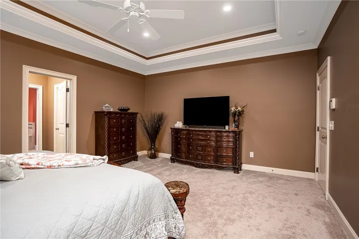 Luxurious tray ceilings crown this well-lit, carpeted sleeping area with an adjoining private bath.