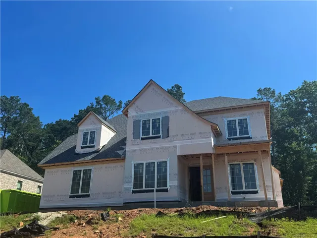 A new construction home awaits its finishing touches, featuring multiple window styles and a prominent front entry.