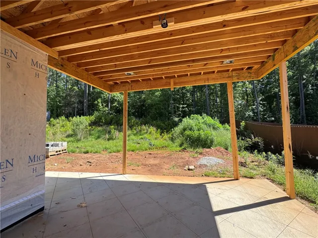 A spacious covered patio invites outdoor relaxation amidst a verdant landscape.