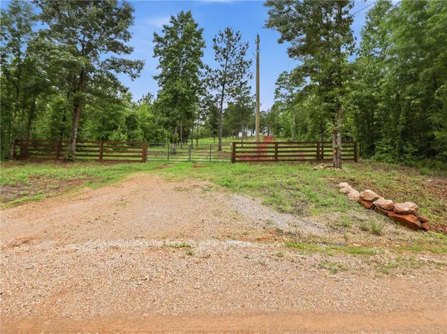 Secure gated entry welcomes you to this verdant, fenced property with a gravel driveway.
