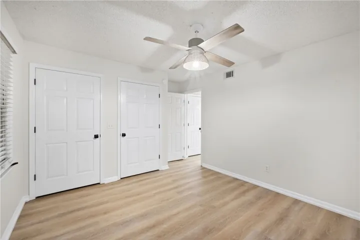 Natural wood-look flooring grounds this generously proportioned bedroom with multiple entryways.