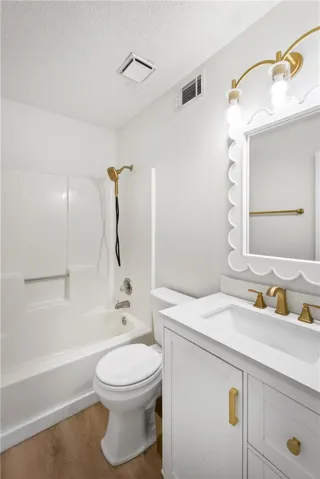 A well-appointed bath features gold-toned fixtures and a decorative vanity mirror.