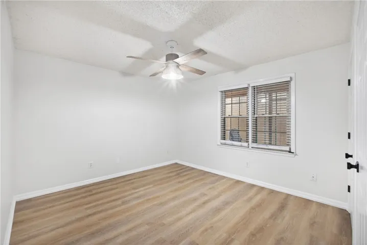 Laminate flooring and a functional ceiling fan with lighting provide comfort and practicality in this ample space.
