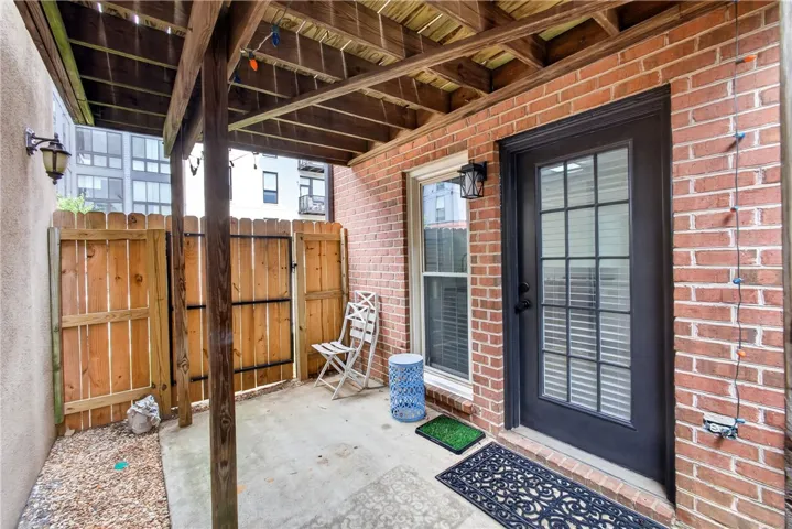 A private, covered patio with brick walls and wood fencing offers a cozy outdoor retreat.