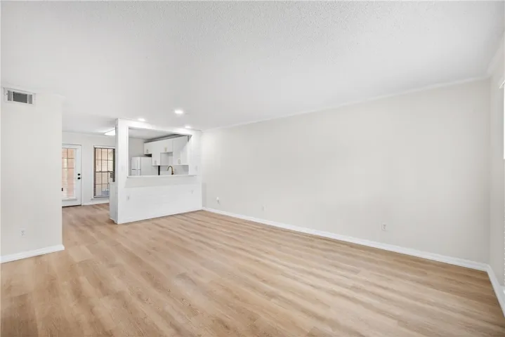 A well-lit interior showcases smooth flooring and a convenient pass-through window to the kitchen area.