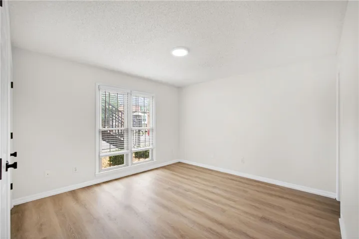 A well-lit room showcasing rich hardwood flooring and a broad window.
