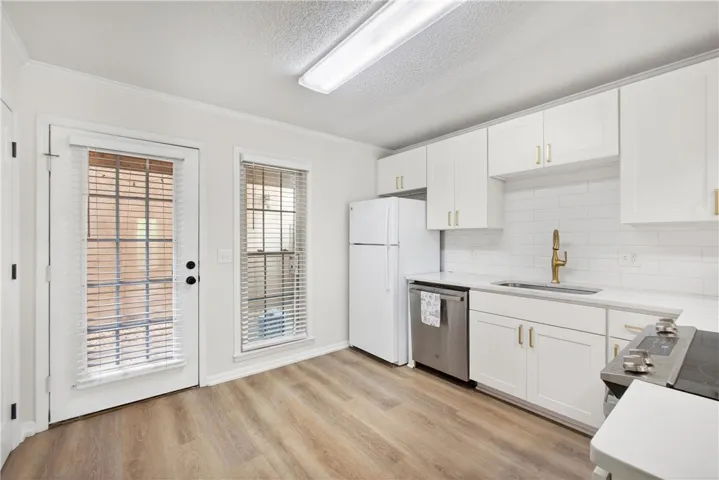 A well-lit kitchen with sleek white cabinetry and warm wood flooring awaits.