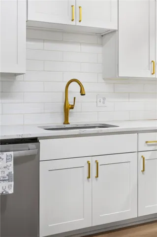 A well-appointed kitchen features a modern gold faucet set against pristine white cabinetry and subway tile backsplash.