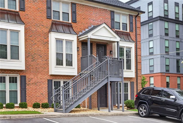 A classic brick facade with modern bay windows and an inviting outdoor staircase welcomes residents.