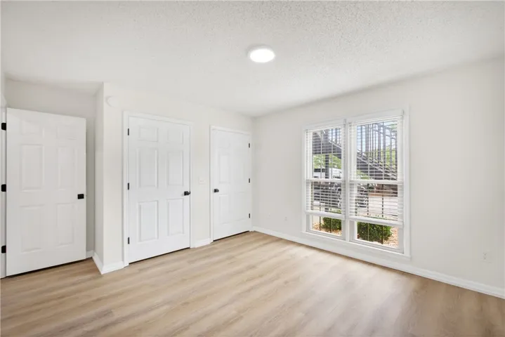 Well-lit room with wood flooring and white interior doors.