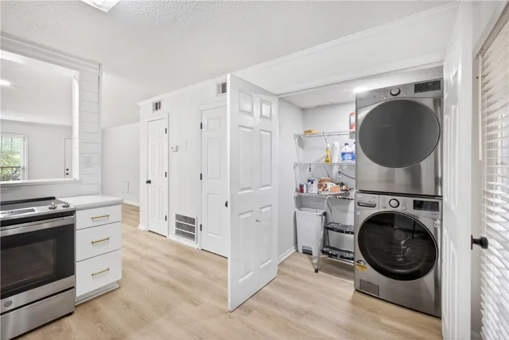 Streamlined laundry area with a stacked washer and dryer unit, blending seamlessly with the light wood-look flooring.
