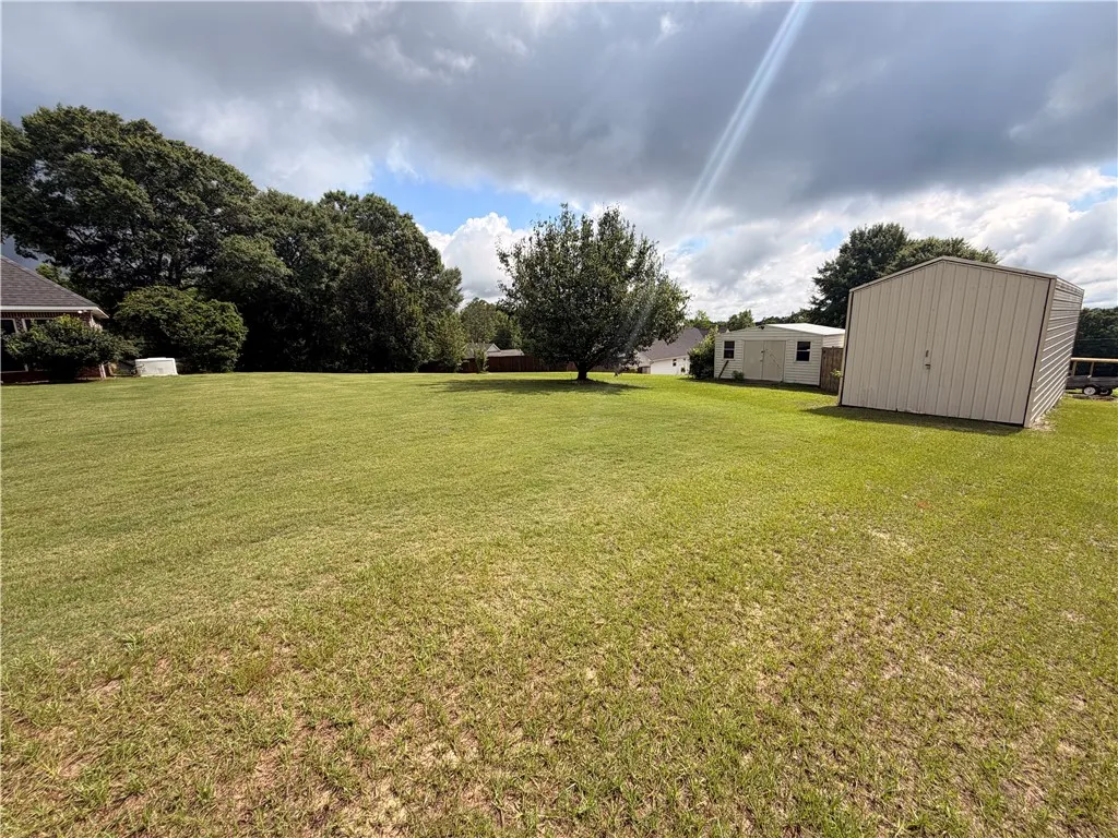 A spacious lot provides ample room for expansion, featuring mature trees and practical outbuildings.