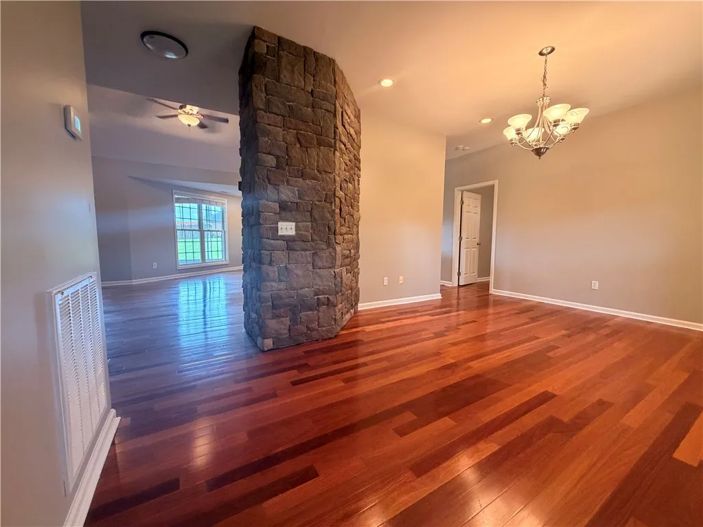 Warm hardwood floors extend throughout an inviting open living space, centered by a striking stone fireplace.
