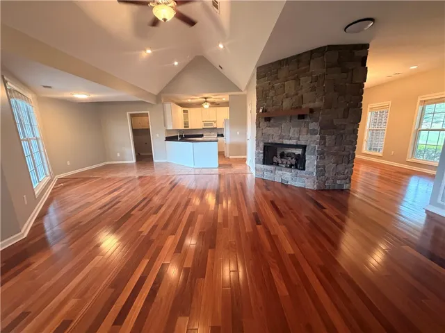 A spacious common area with vaulted ceilings features a stone fireplace and rich hardwood flooring.