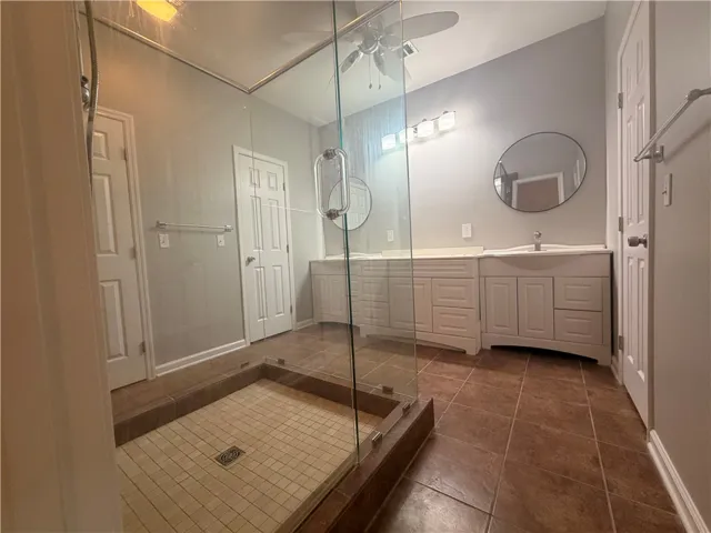 A spacious primary bathroom boasts a walk-in shower and ample vanity space, offering a functional design.