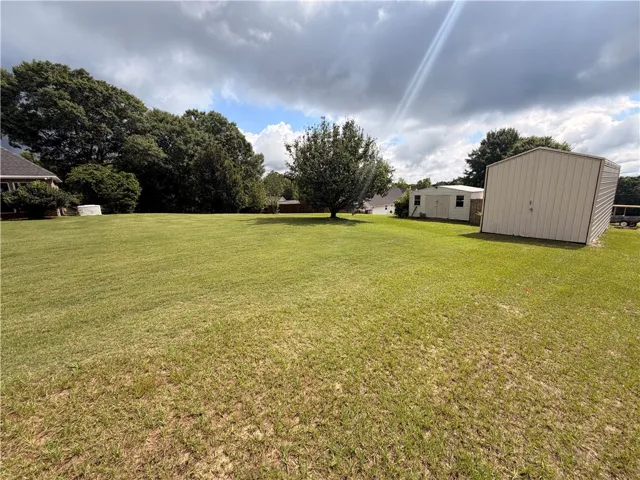 A spacious lot provides ample room for expansion, featuring mature trees and practical outbuildings.