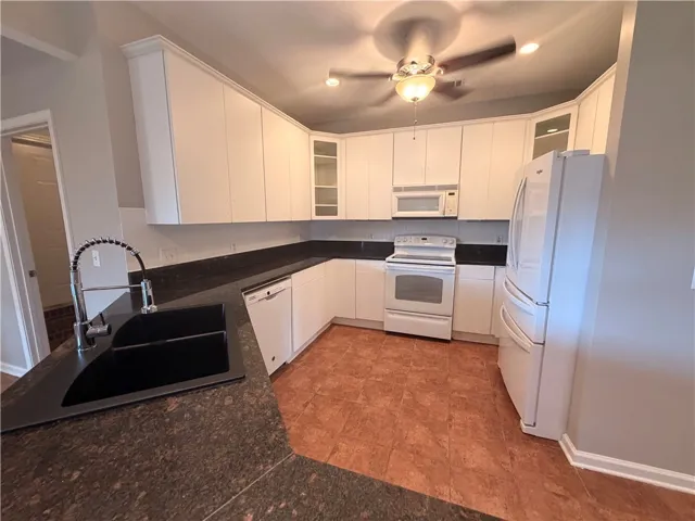 Functional kitchen with ample cabinetry and dark granite countertops.