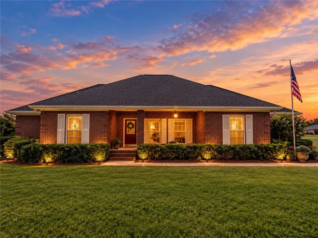 Manicured hedges line the classic brick exterior beneath a multi-gabled shingle roof.