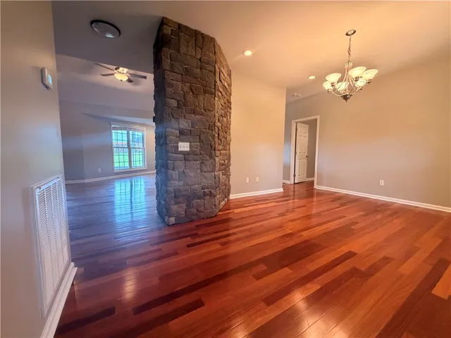 Warm hardwood floors extend throughout an inviting open living space, centered by a striking stone fireplace.