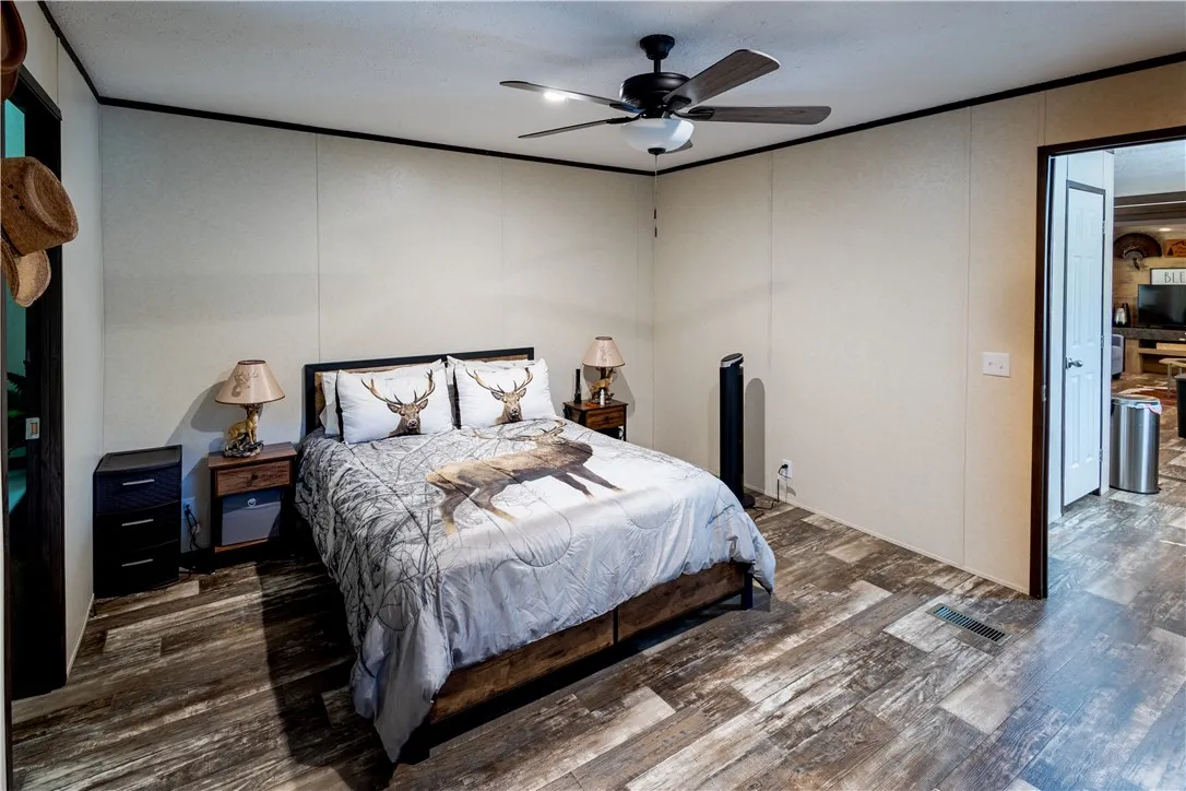 A comfortable bedroom features sturdy plank flooring and a ceiling fan, offering a restful retreat.