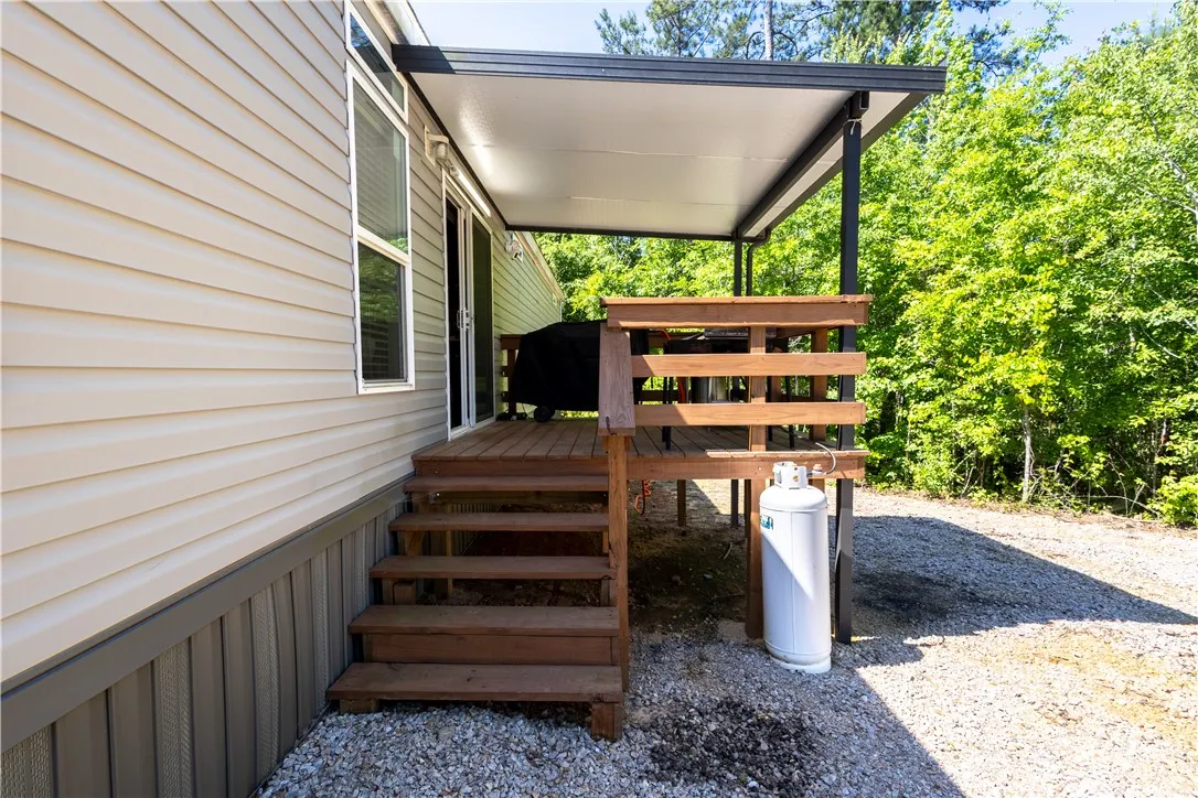An inviting covered patio with a natural wood deck offers a private outdoor retreat.