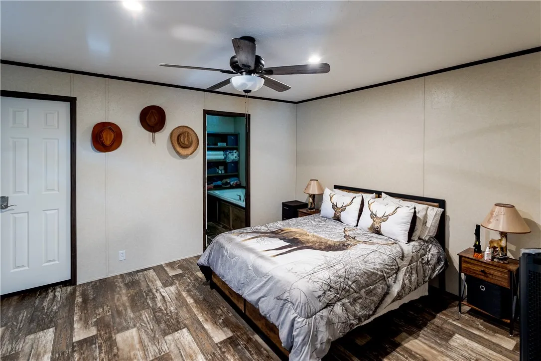 Natural-toned plank flooring anchors this bedroom with a ceiling fan for comfort.