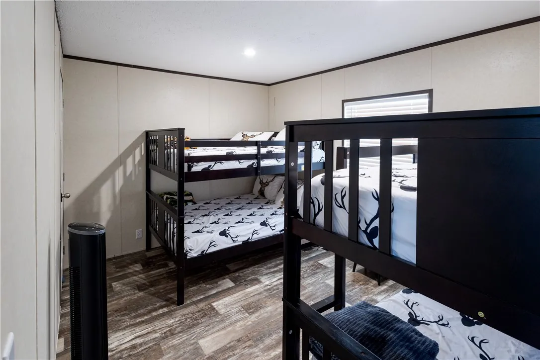 Functional design maximizes sleeping arrangements in this comfortable bedroom with rich wood-look flooring.