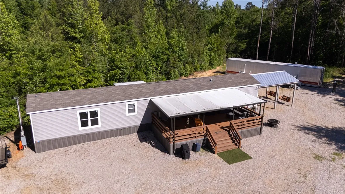 A welcoming front porch extends from this single-story residence, set against a backdrop of mature trees.