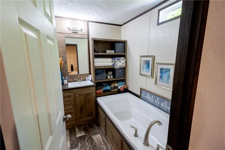 Relax and rejuvenate in this inviting primary bathroom, featuring a deep soaking tub and a functional vanity.