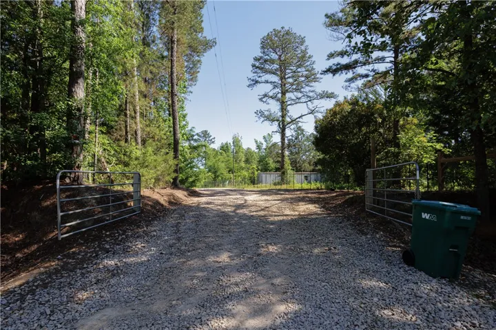 A private gravel drive through mature trees, leading to a secluded area.