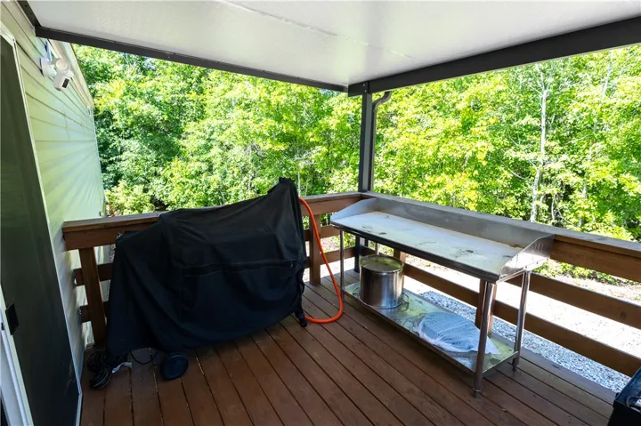 A spacious covered deck extends into nature's embrace, perfect for outdoor cooking and entertaining.