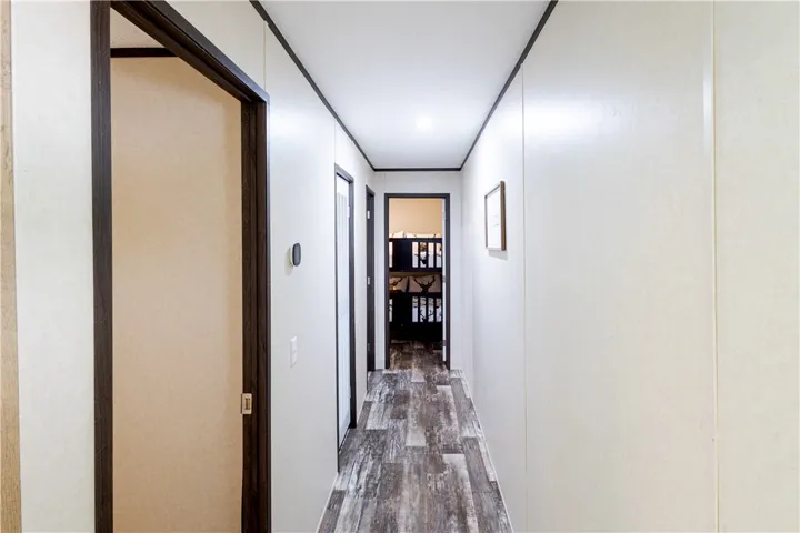 A streamlined hallway offers clear passage with durable, plank-style flooring and overhead recessed lighting.