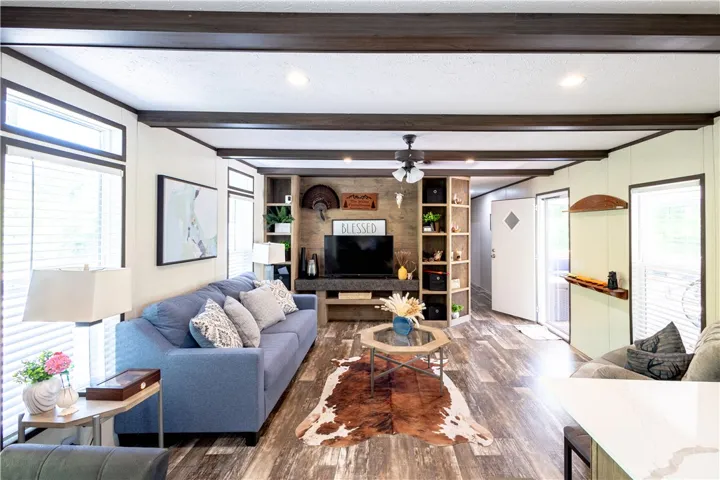 Rich wood-toned ceiling beams complement the flooring, creating an inviting, cohesive living area.