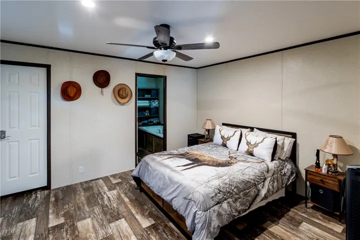 Natural-toned plank flooring anchors this bedroom with a ceiling fan for comfort.